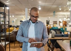 Man standing and looking at a tablet