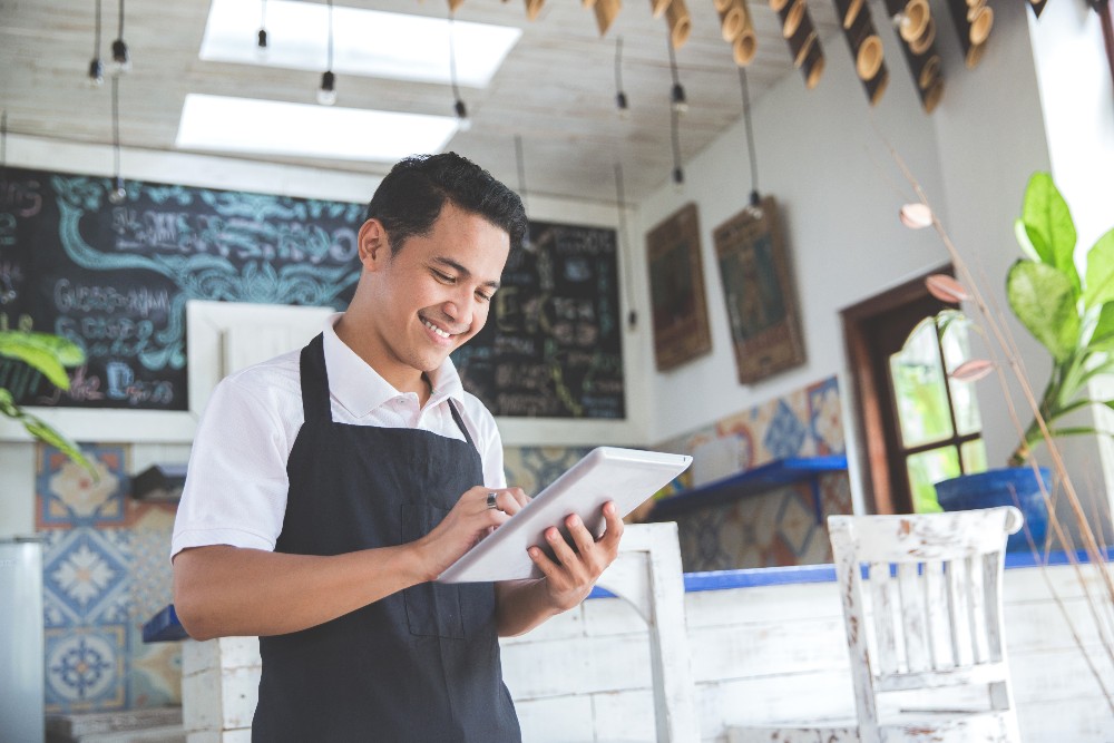 Small business owner standing in restaurant on a tablet