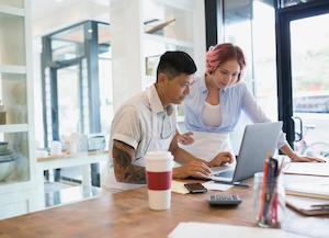 two small business owners at table looking at laptop