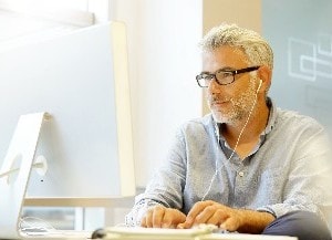 Man looking at computer while wearing headphones