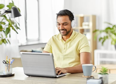 Man sitting at a desk with laptop and headphones