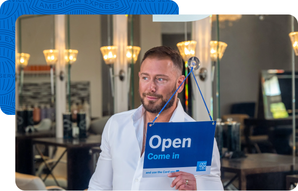 Store owner holding a sign saying “Open" in storefront window 