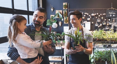Man and child shopping at a plant store and speaking to small business owner