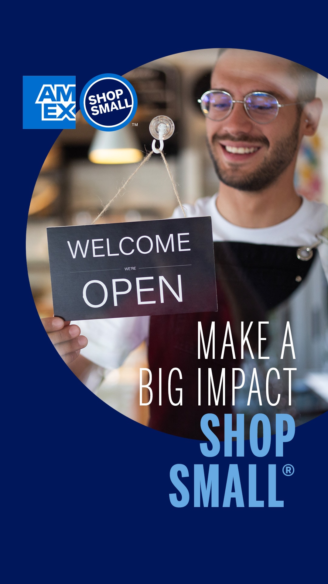 Store owner at storefront door flipping the sign to say Welcome, OPEN and text that says Make a big impact. Shop Small.