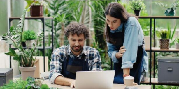Personne travaillant d'un café. La journée est ensoleillée, une tasse et un laptop son posés sur la table devant elle.