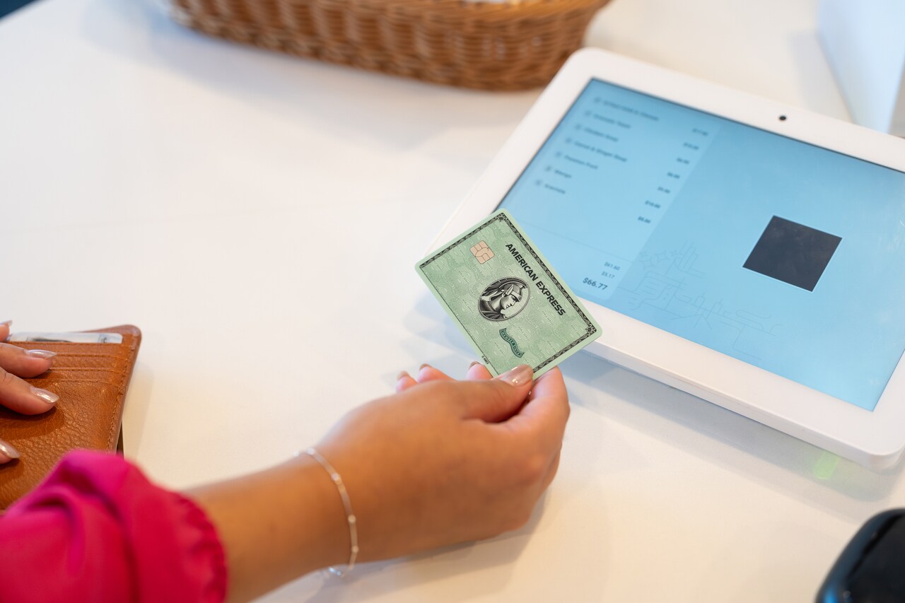 Einen Person mit Kreditkarte in der Hand möchte an einem Tablet zahlen