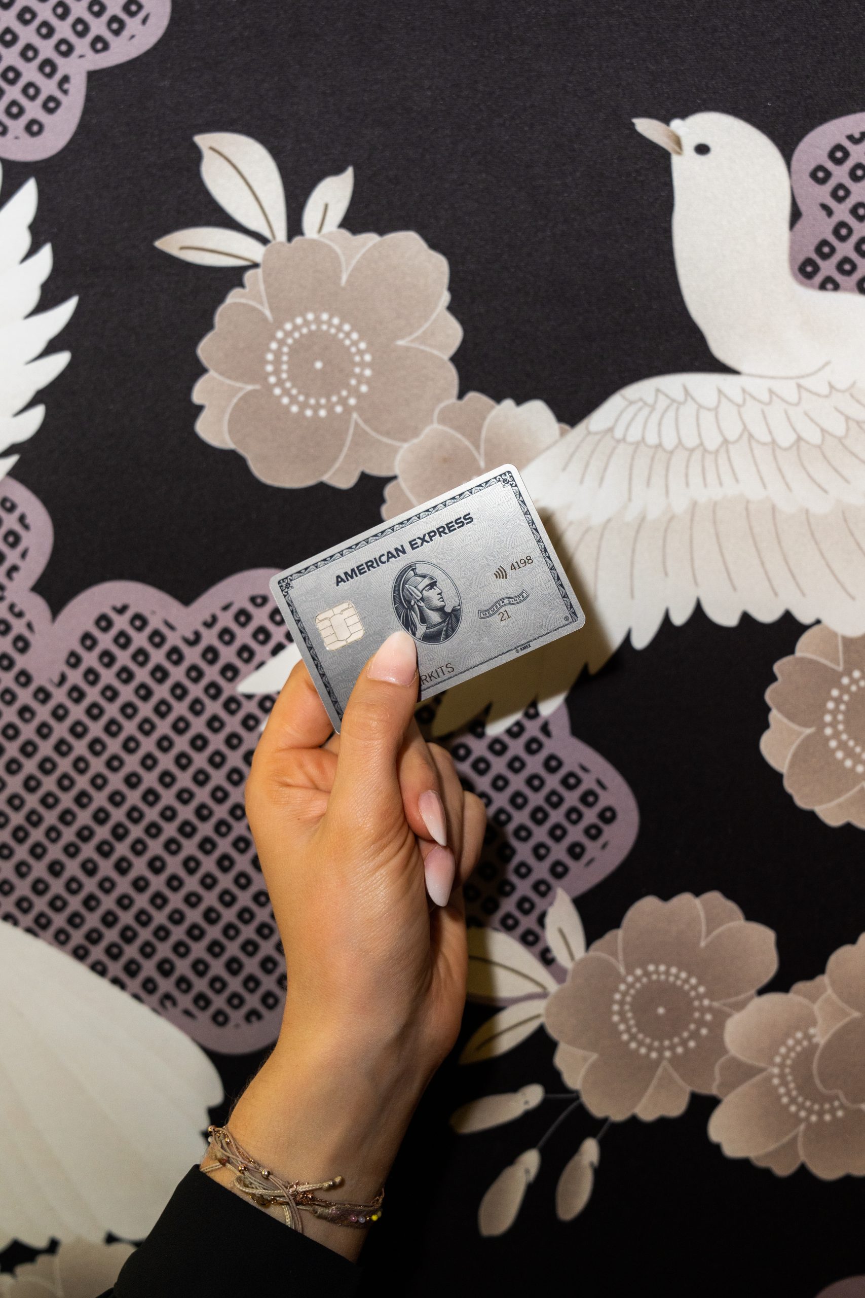 Eine gepflegte Frauenhand mit weiß lackierten Nägeln hält eine American Express Platinum Card
