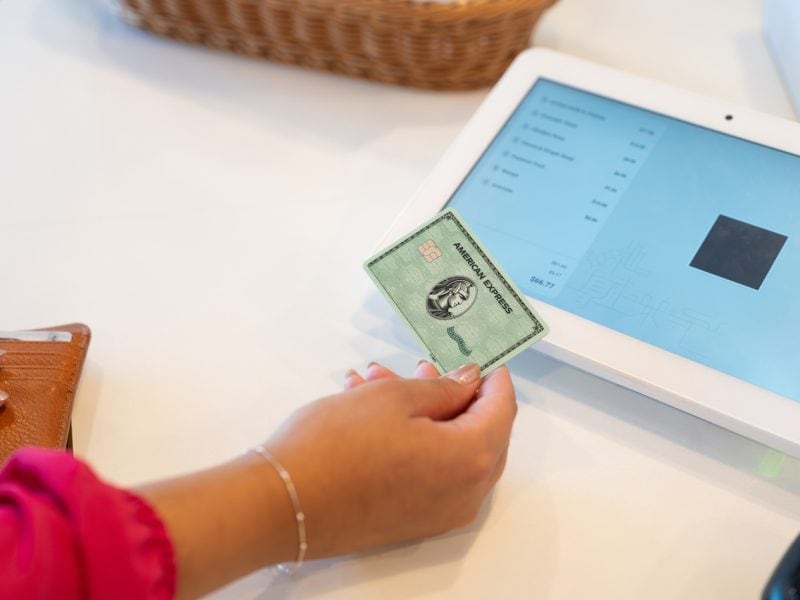 Einen Person mit Kreditkarte in der Hand möchte an einem Tablet zahlen