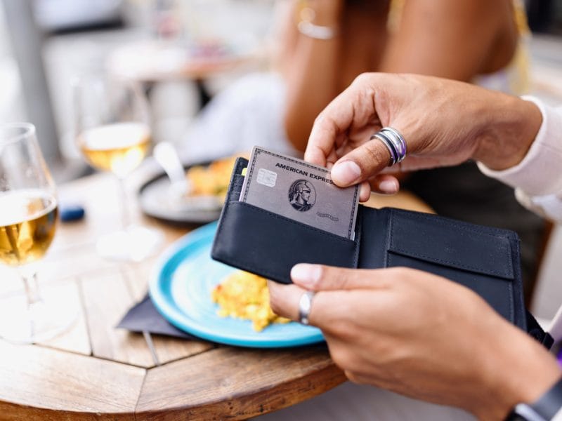 Alt-Text: Eine Person hält eine Kreditkarte an einem Tisch mit Getränken.