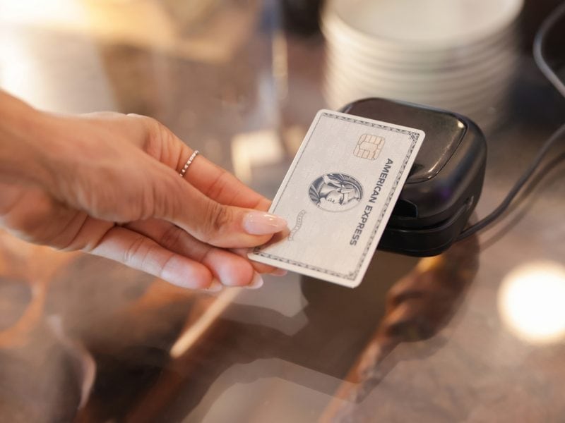Eine Person hält eine Kreditkarte über ein mobiles Zahlungsgerät
