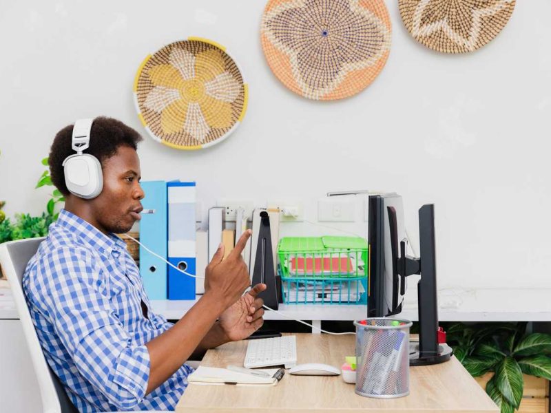 Person mit Kopfhörer sitzt vor dem Bildschirm