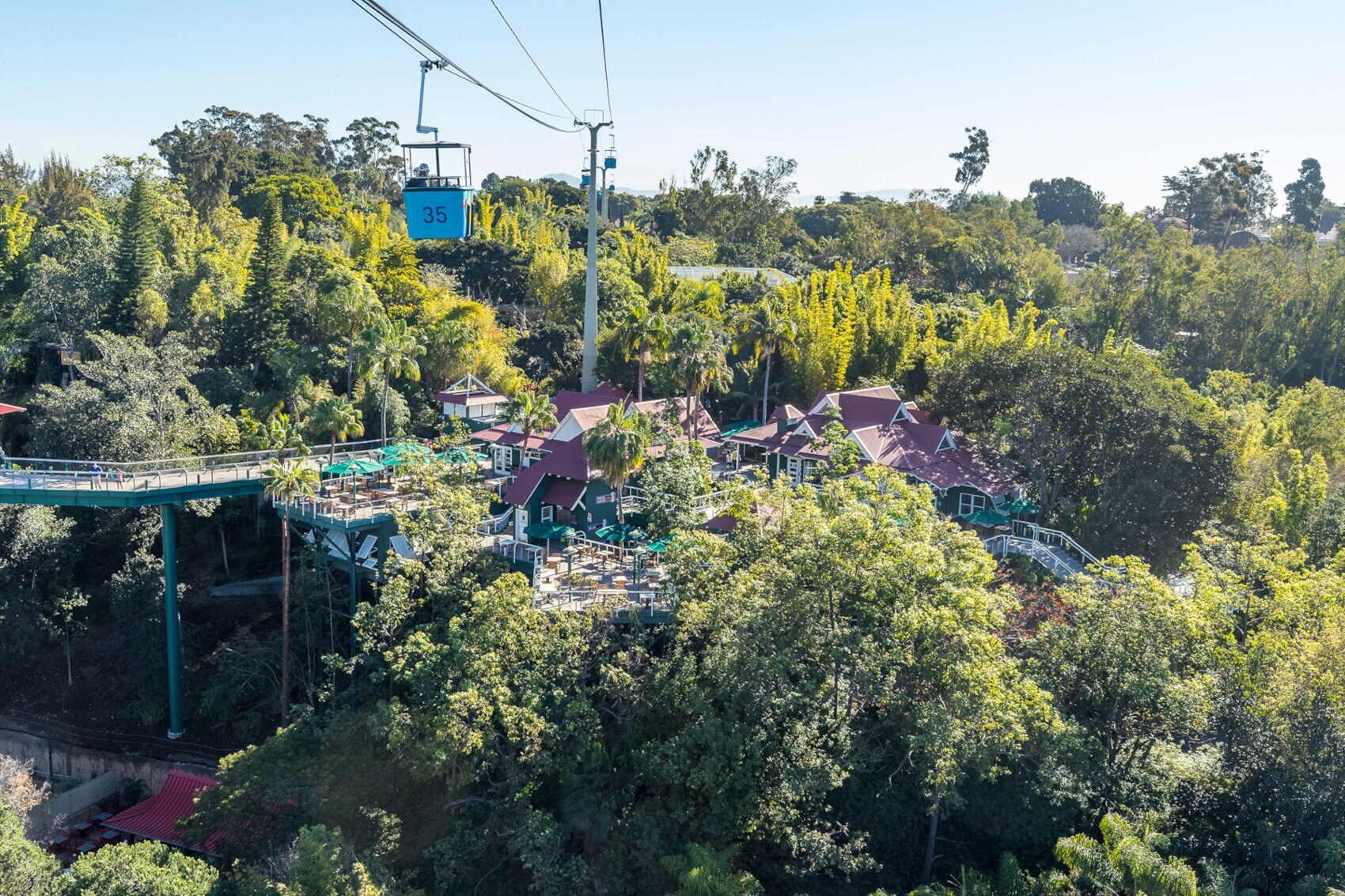 Eine Seilbahn schwebt über eine Freizeitanlage in einer bewaldeten Gegend