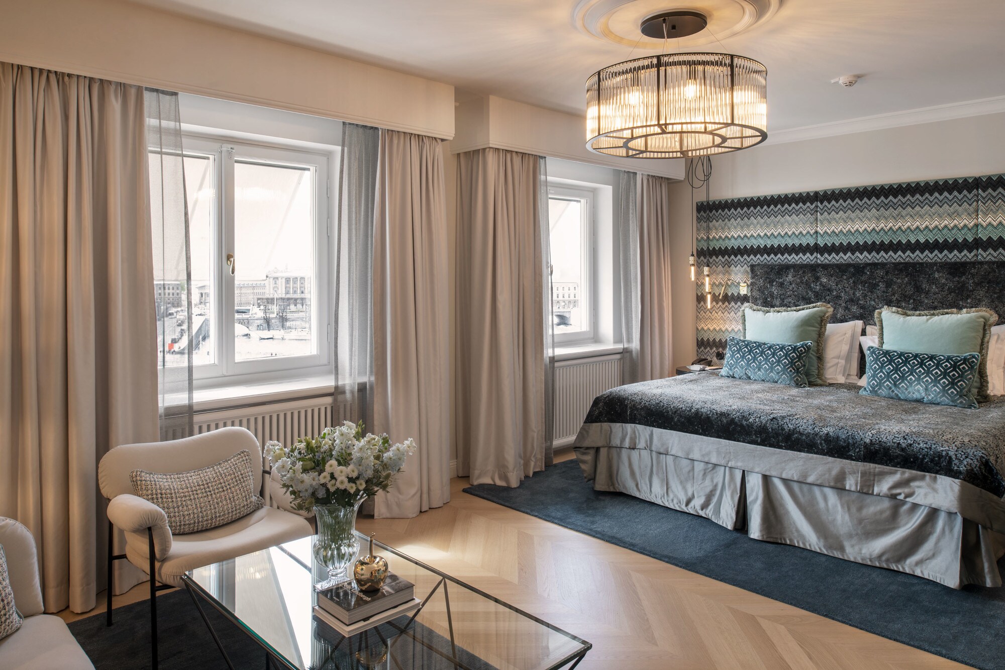 Luxuriöses, helles Hotelzimmer mit Kingsize-Bett und Textilien in Blau- und Beigetönen.