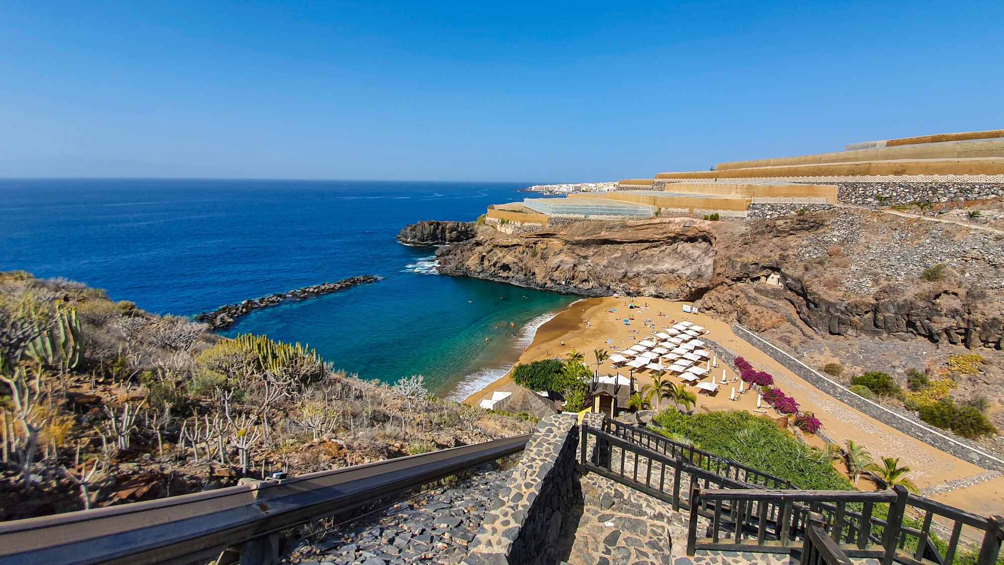 Aufsicht eines kleinen Sandstrandes mit Sonnenliegen in einer felsgesäumten Bucht Aufsicht eines kleinen Sandstrandes mit Sonnenliegen in einer felsgesäumten Bucht
