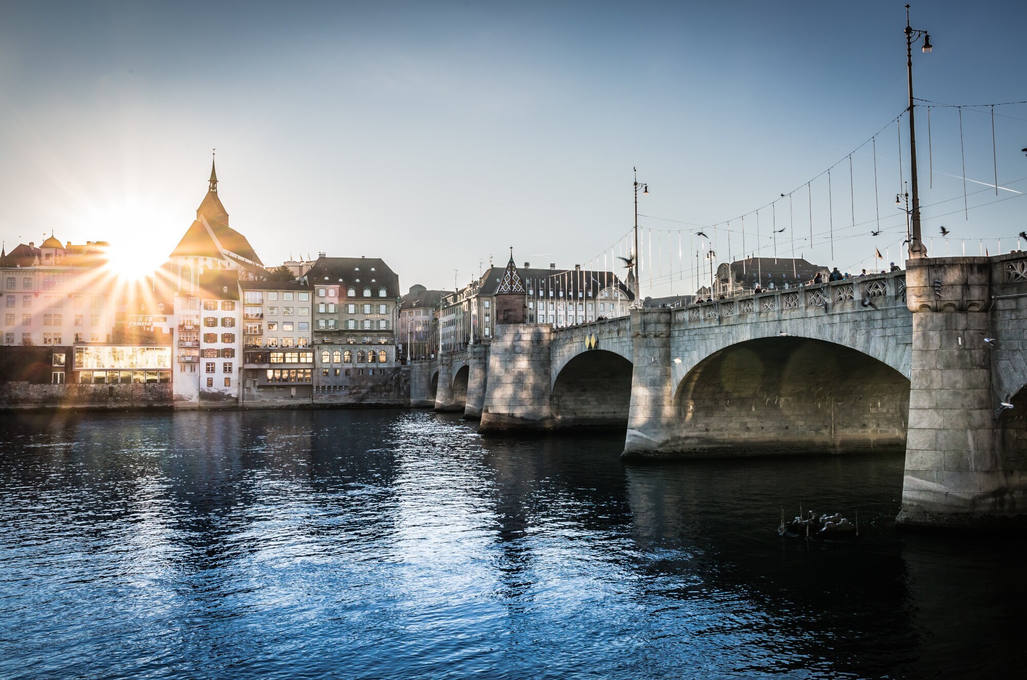 Eine große Steinbrücke über dem Rhein, im Hintergrund mehrere Gebäude in der Abendsonne. Eine große Steinbrücke über dem Rhein, im Hintergrund mehrere Gebäude in der Abendsonne.