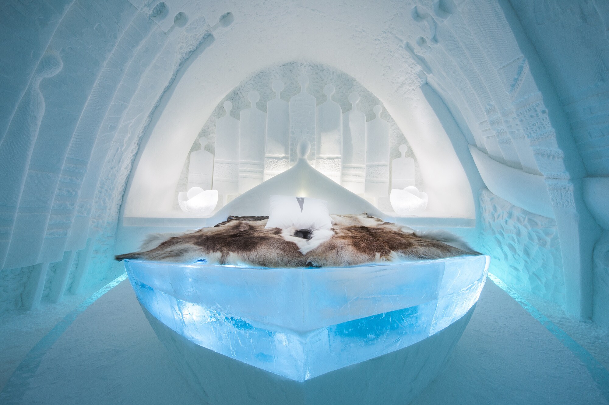 Innenansicht eines Zimmers in einem Eishotel mit Rentierfellen auf dem Bett. Innenansicht eines Zimmers in einem Eishotel mit Rentierfellen auf dem Bett.