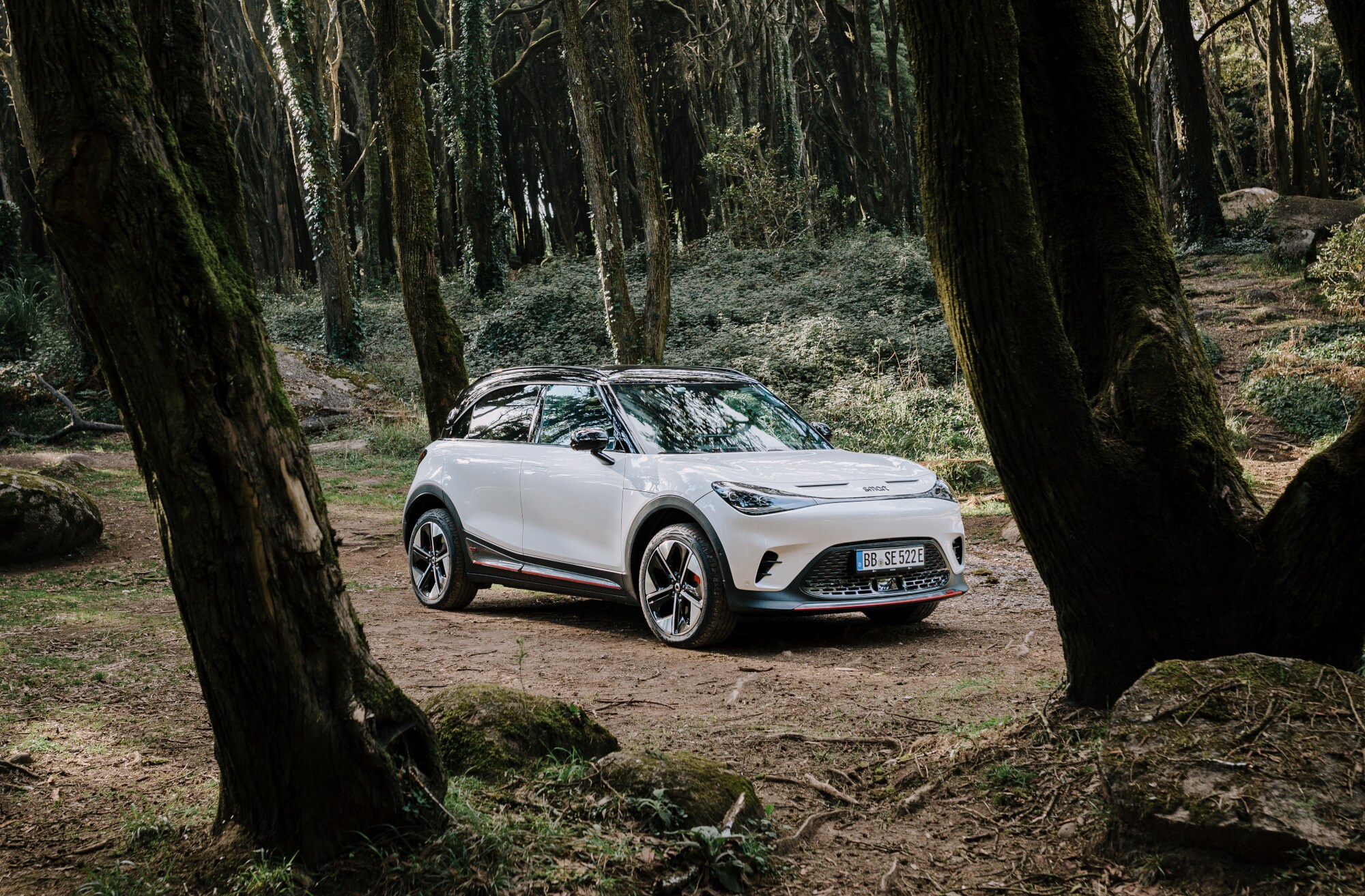 Ein weißer smart #1 BRABUS steht auf einer kleinen Lichtung im Wald.