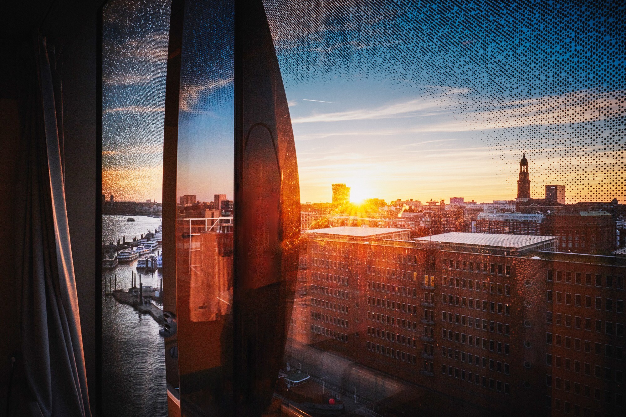 Stadtpanorama von Hamburg am Hafen aus einem geschwungenen Fenster bei Sonnenuntergang.