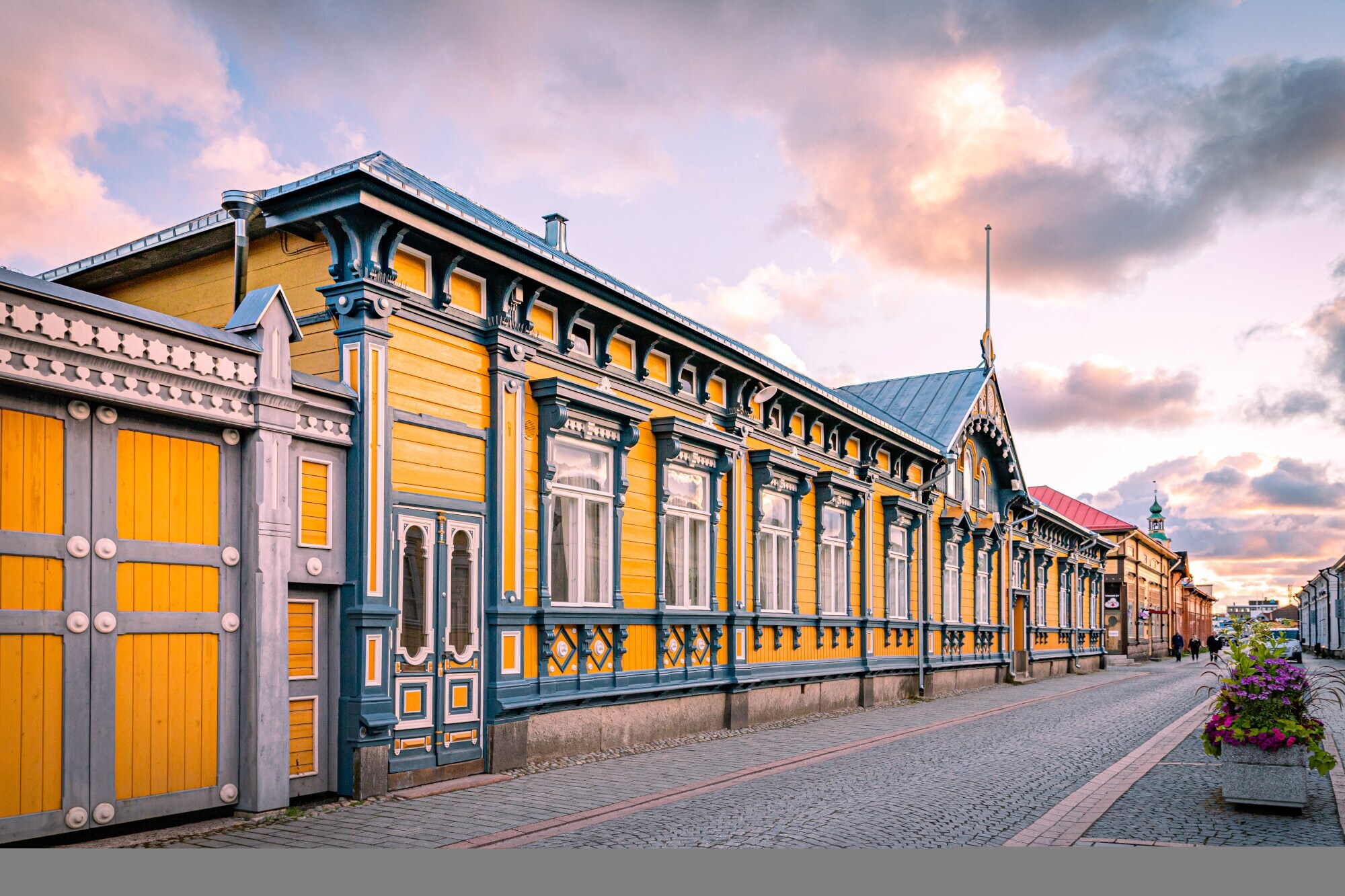 Eine Straße mit kunstvoll gestalteten gelben Holzhäusern.