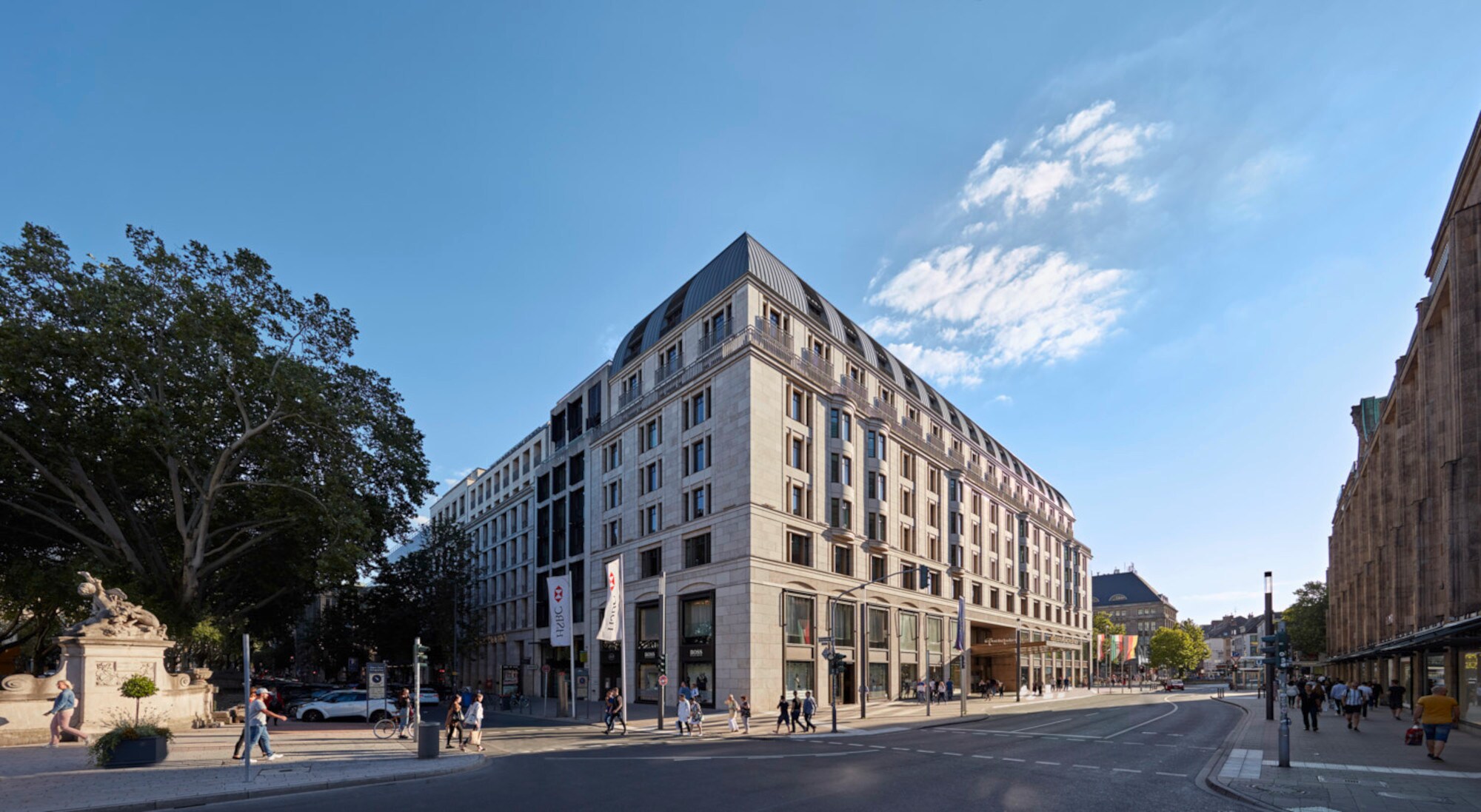 Eine helle Außenfassade des mehrstöckigen Gebäudes eines Luxushotels an einer Straßenkreuzung in Düsseldorf.
