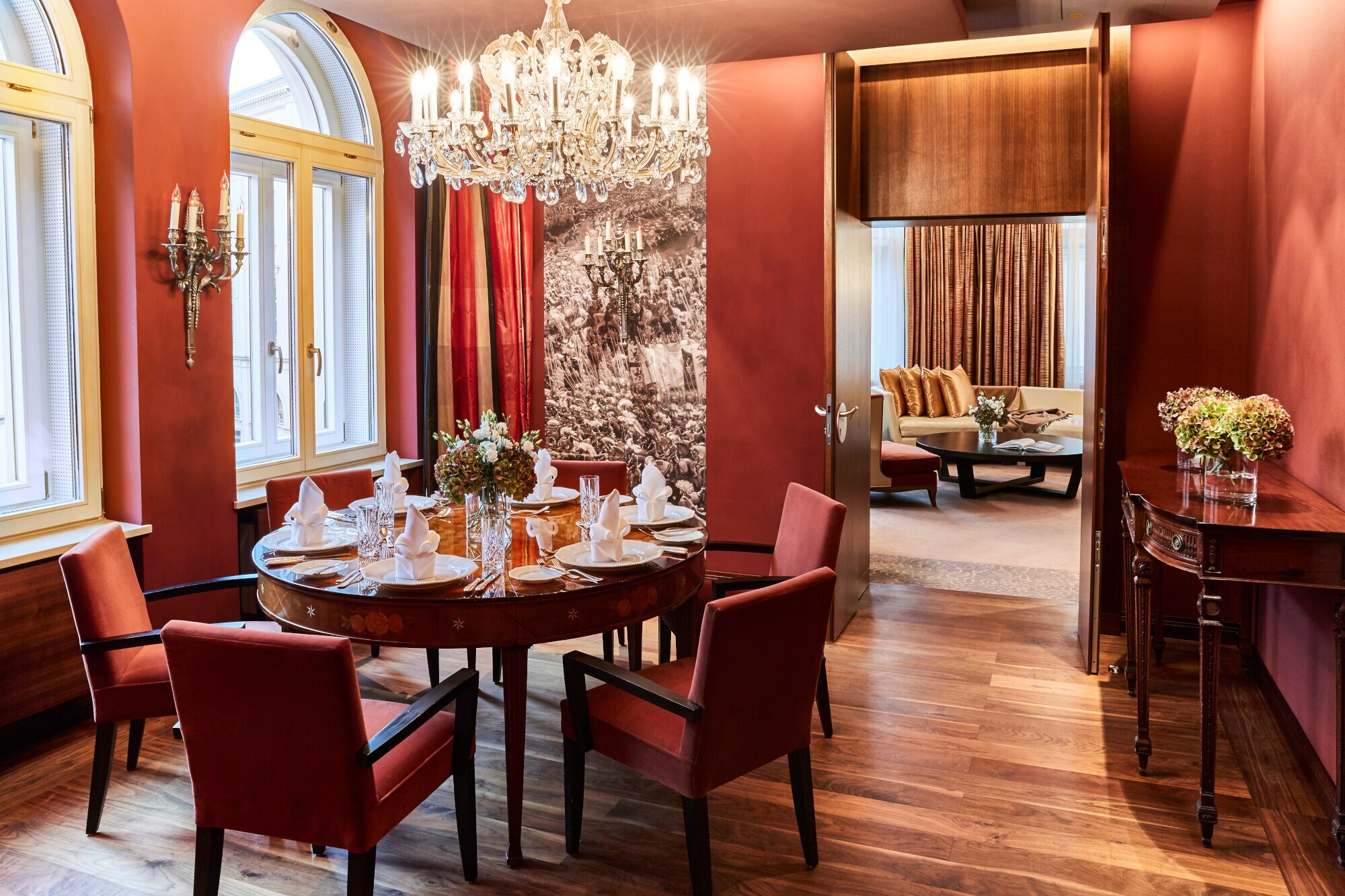 Runder, elegant eingedeckter Esstisch unter einem Kronleuchter in einer luxuriösen Suite in Terrakottatönen.