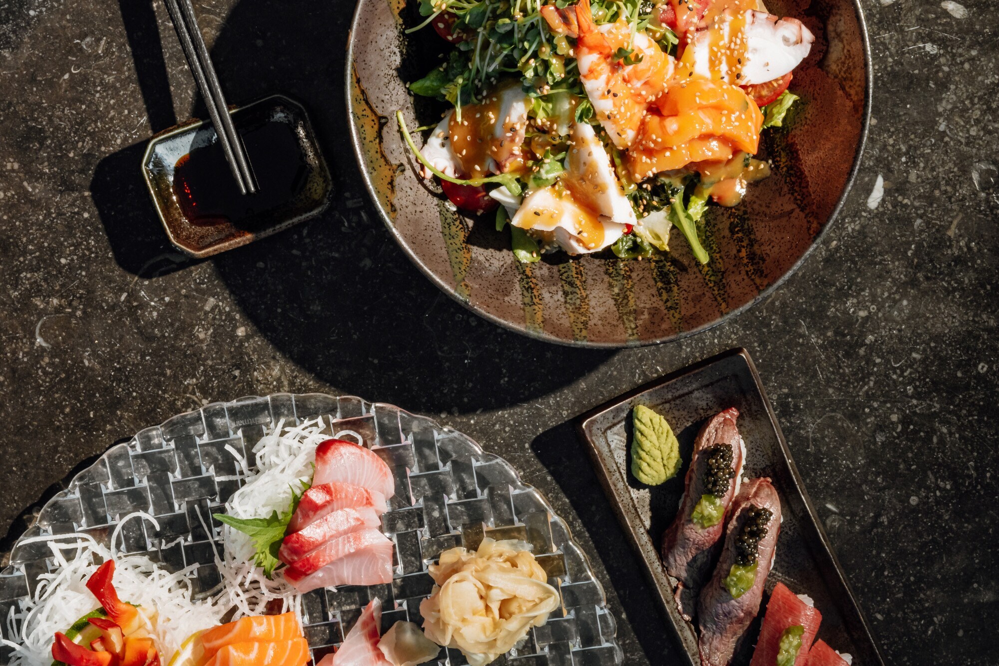 Aufsicht mehrerer Teller mit Sushi und anderer asiatischen Speisen.