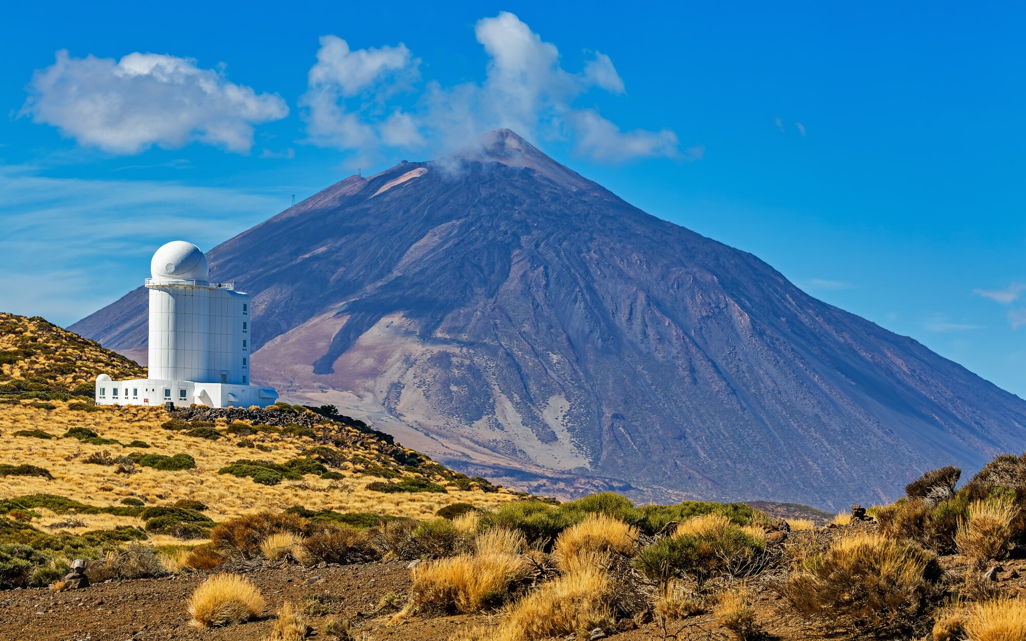 Ein weißes Observatorium in karger Landschaft, im Hintergrund ein Vulkan. Ein weißes Observatorium in karger Landschaft, im Hintergrund ein Vulkan.