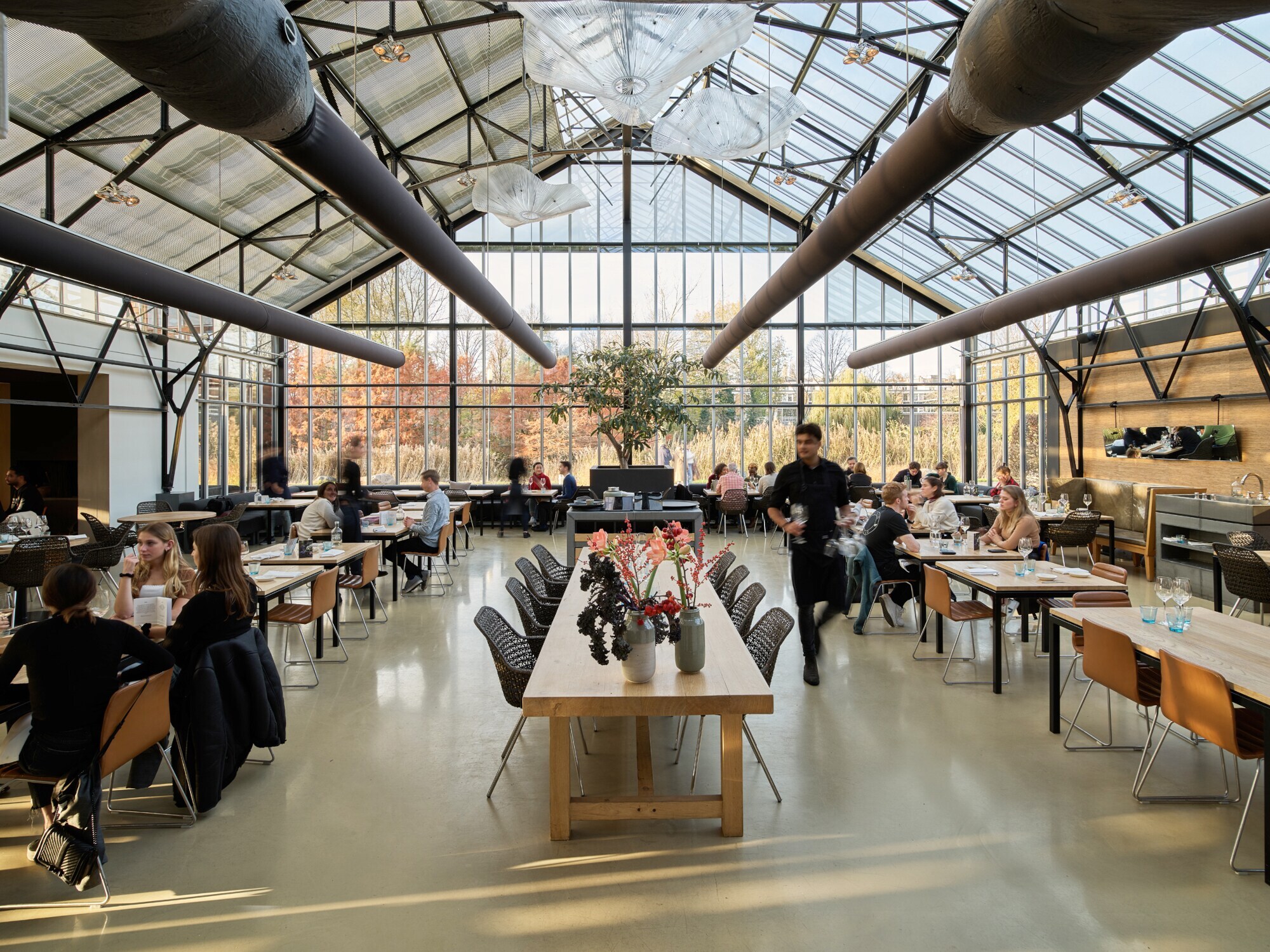 Modernes Restaurant mit Holztischen in einem Gewächshaus. Modernes Restaurant mit Holztischen in einem Gewächshaus.