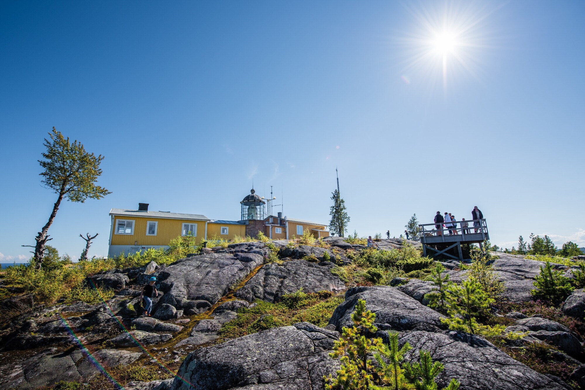 Blick auf ein gelbes Gebäude auf einem Gelände mit Felsformationen und einem Aussichtspunkt.