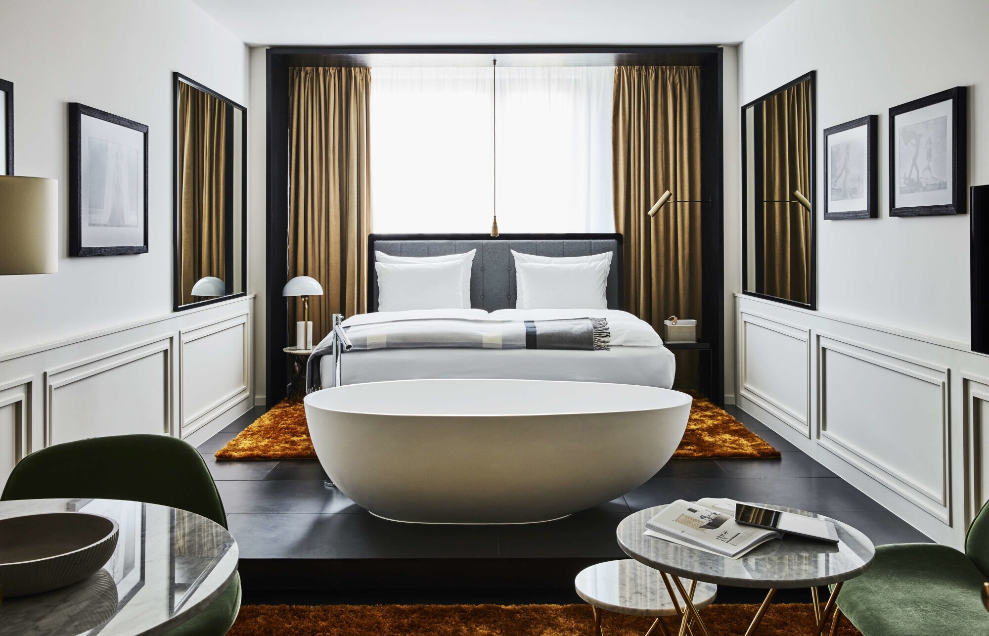 Moderne Hotelsuite mit einer freistehenden Badewanne vor einem Doppelbett.