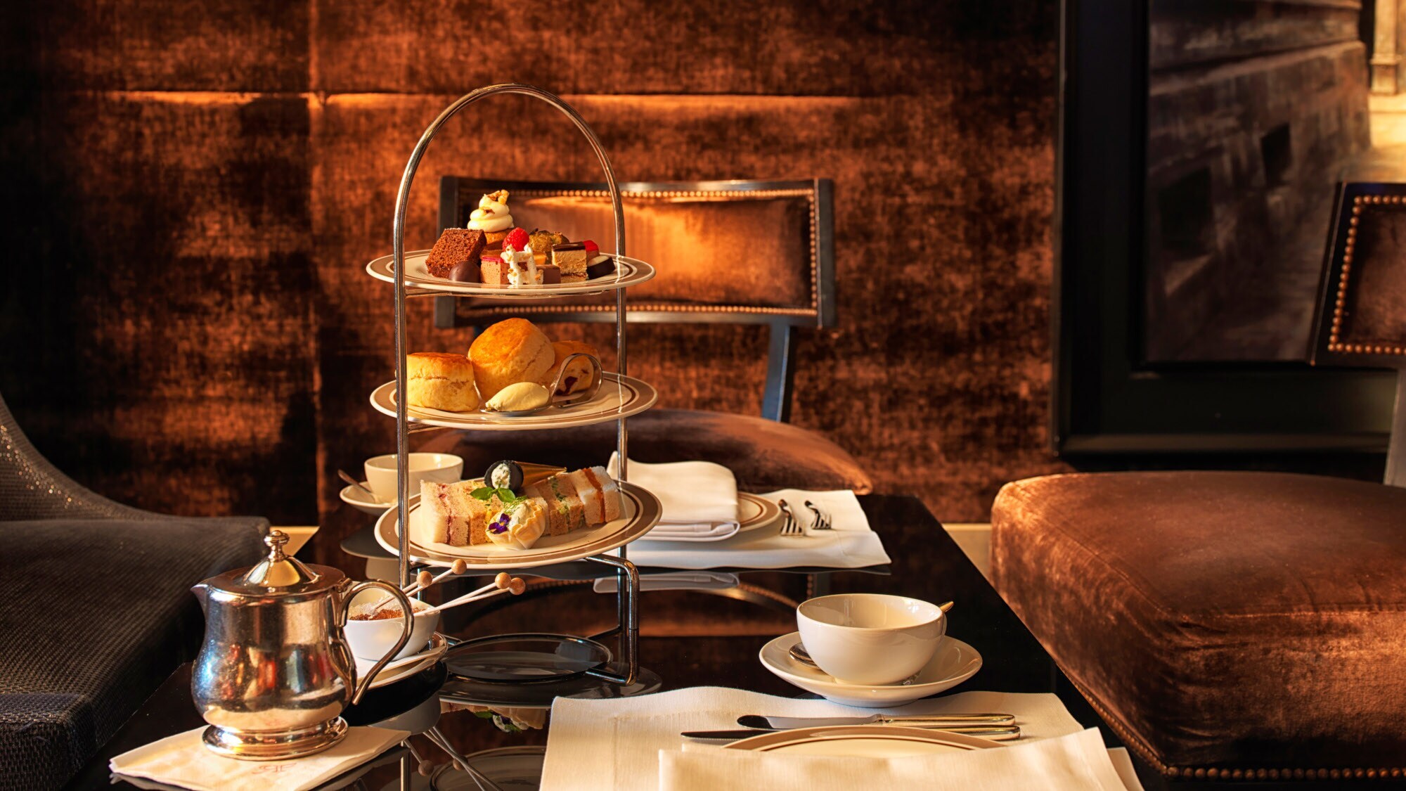 Eingedeckter Tisch zur Teatime mit Gebäck und Süßspeisen auf einer Etagere.