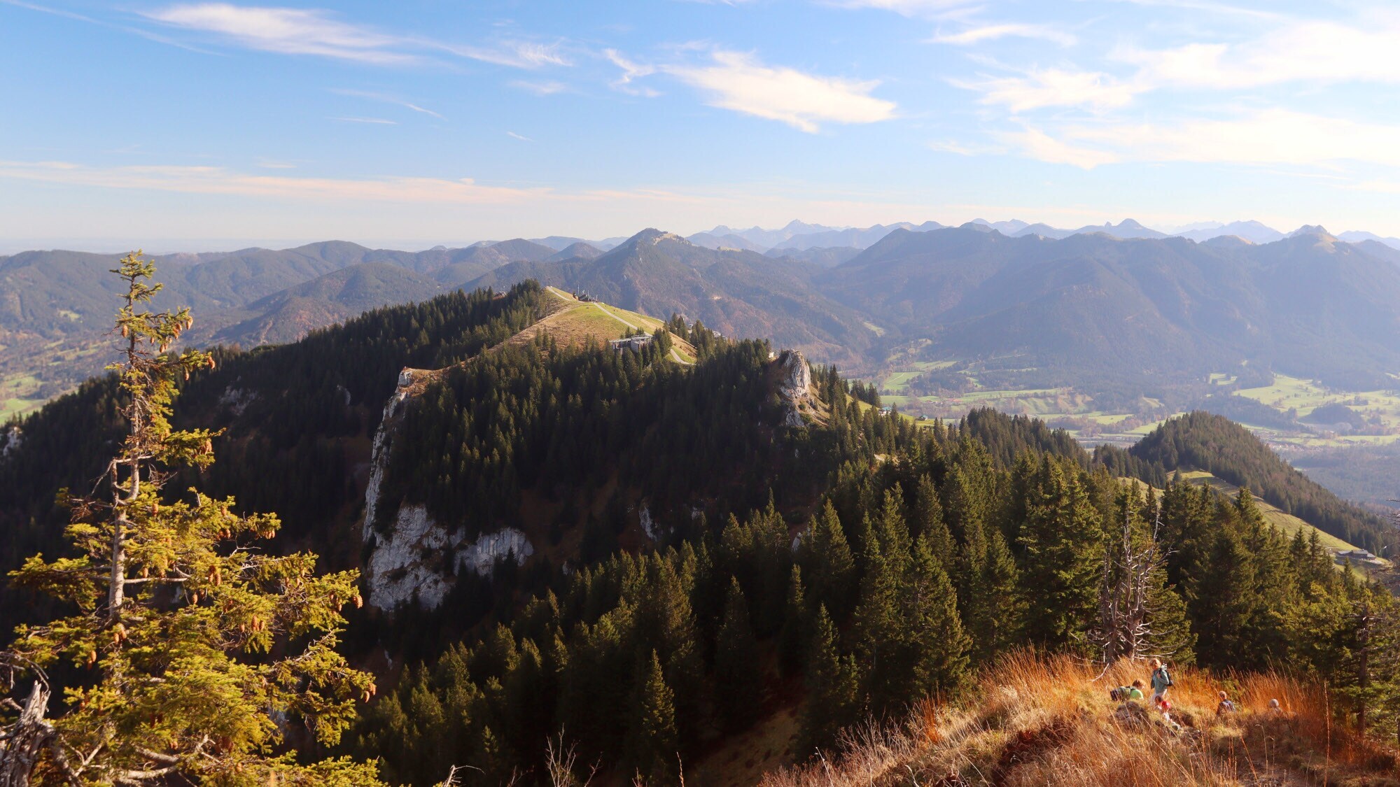 Bewaldeter Bergkamm vor Gebirgslandschaft.