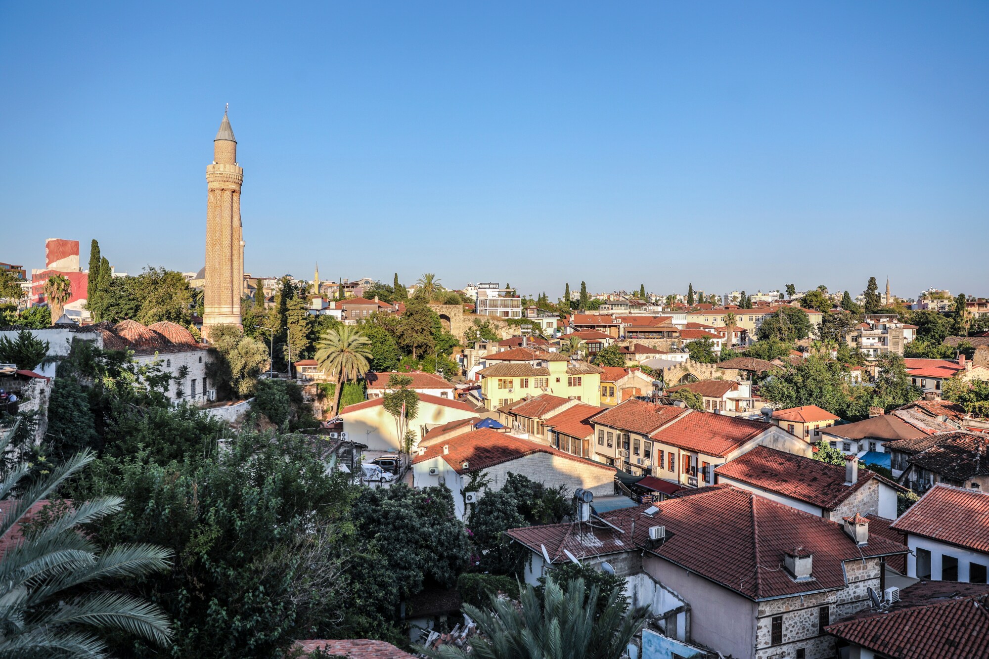 Eine Stadt mit vielen kleinen Häusern und Palmen, an dessen Rand der Turm eines Minaretts herausragt.