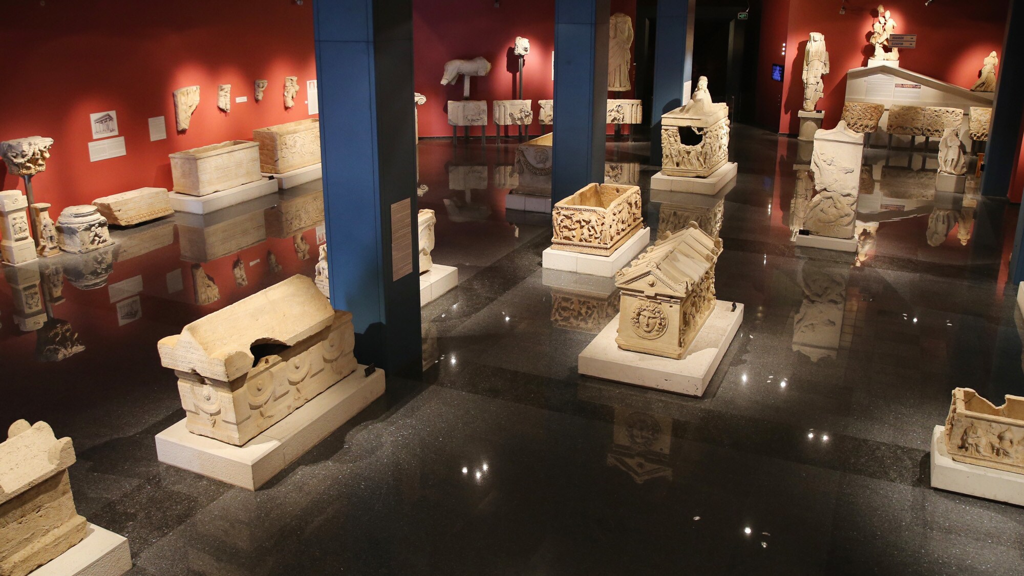 Ein abgedunkelter Ausstellungsraum eines Museums mit zahlreichen Artefakten und Statuen.