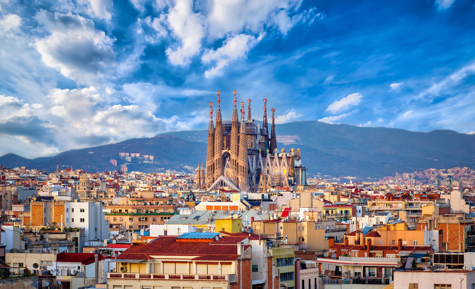 Stadtpanorama von Barcelona mit der emporragenden Sagrada Familia vor einem Gebirgszug im Hintergrund. Stadtpanorama von Barcelona mit der emporragenden Sagrada Familia vor einem Gebirgszug im Hintergrund.