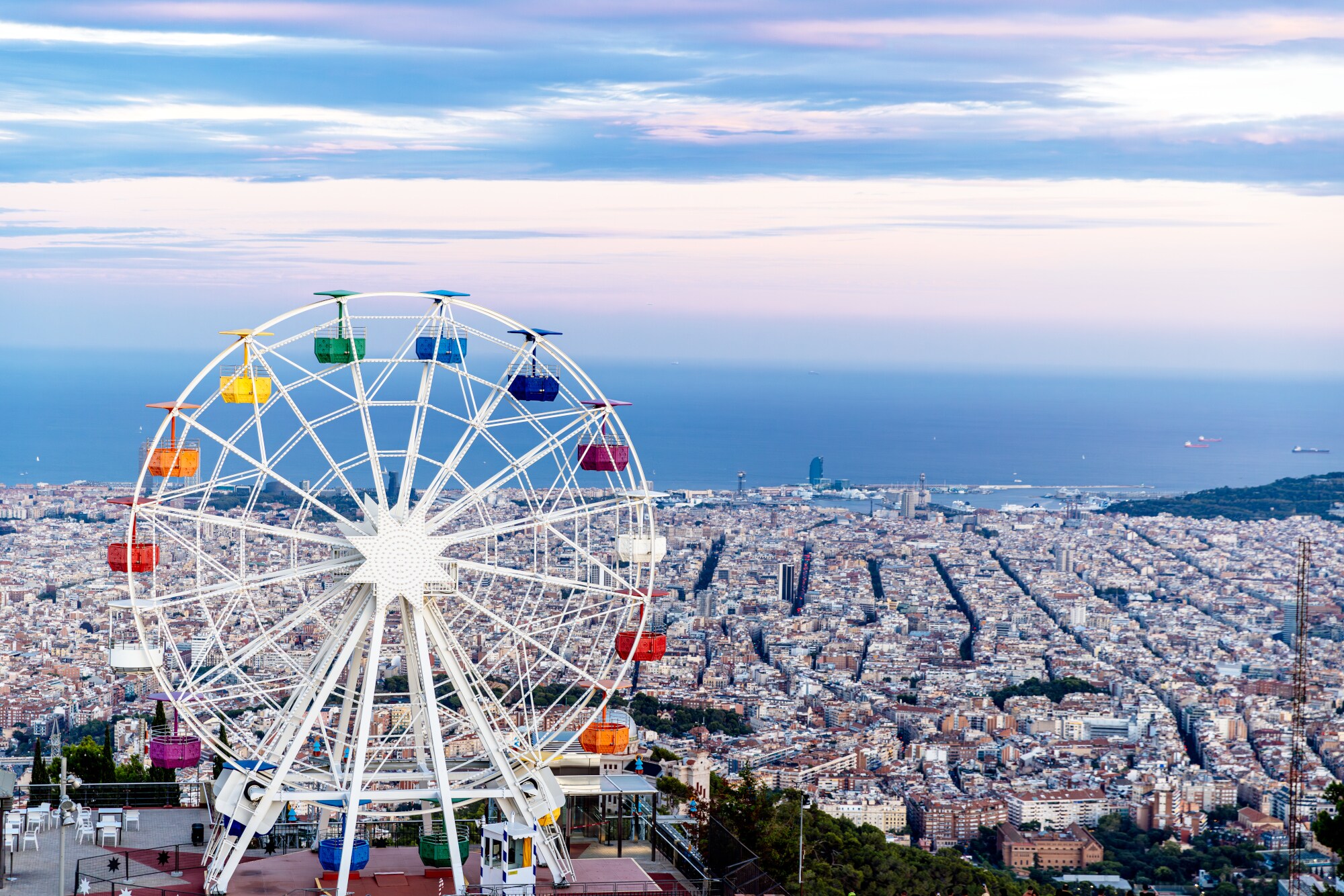 Ein Riesenrad auf einem Berg vor dem Stadtpanorama von Barcelona am Meer. Ein Riesenrad auf einem Berg vor dem Stadtpanorama von Barcelona am Meer.
