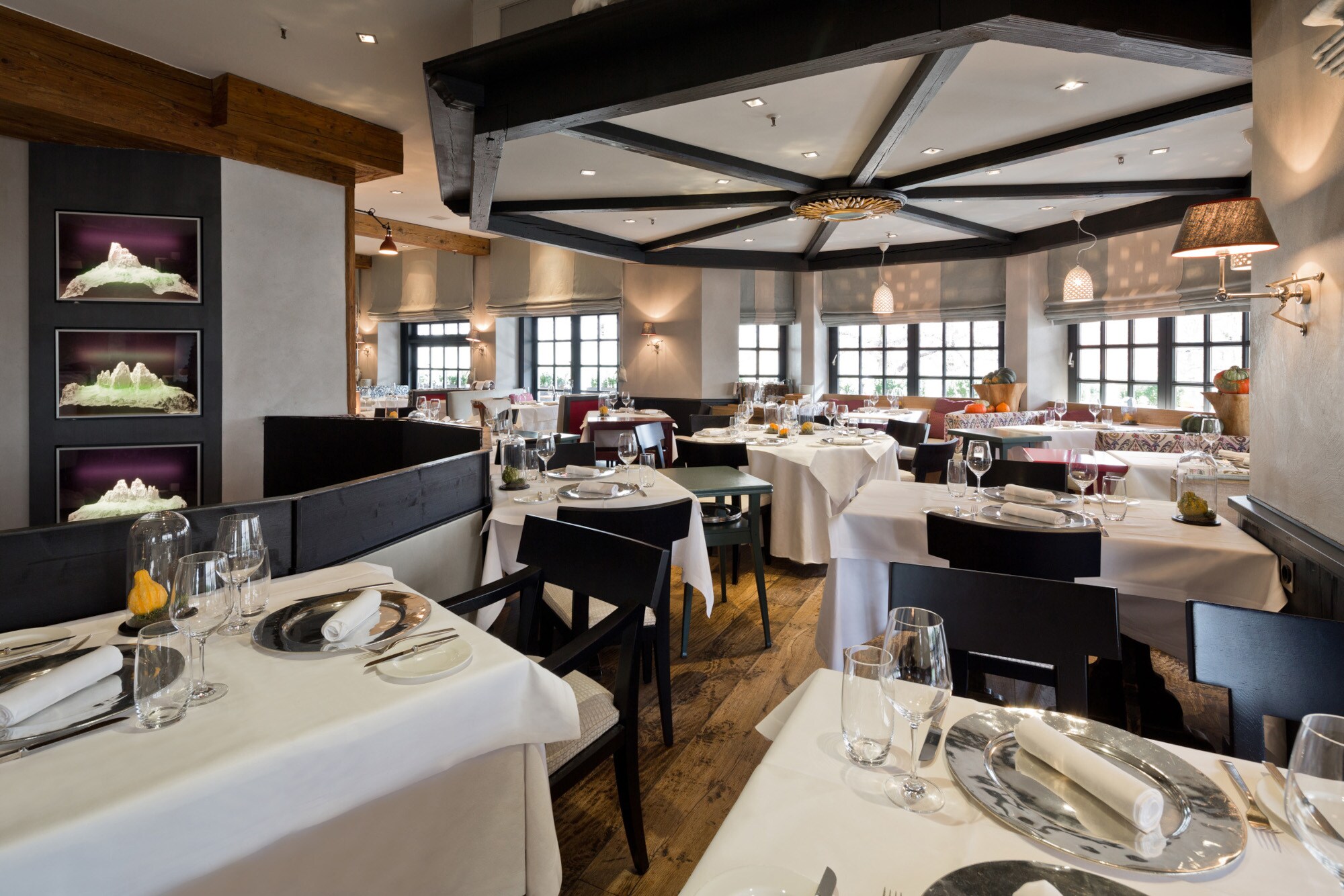 Elegantes Restaurant mit schwarzen Holzstühlen an eingedeckten Tischen mit weißen Tischdecken.