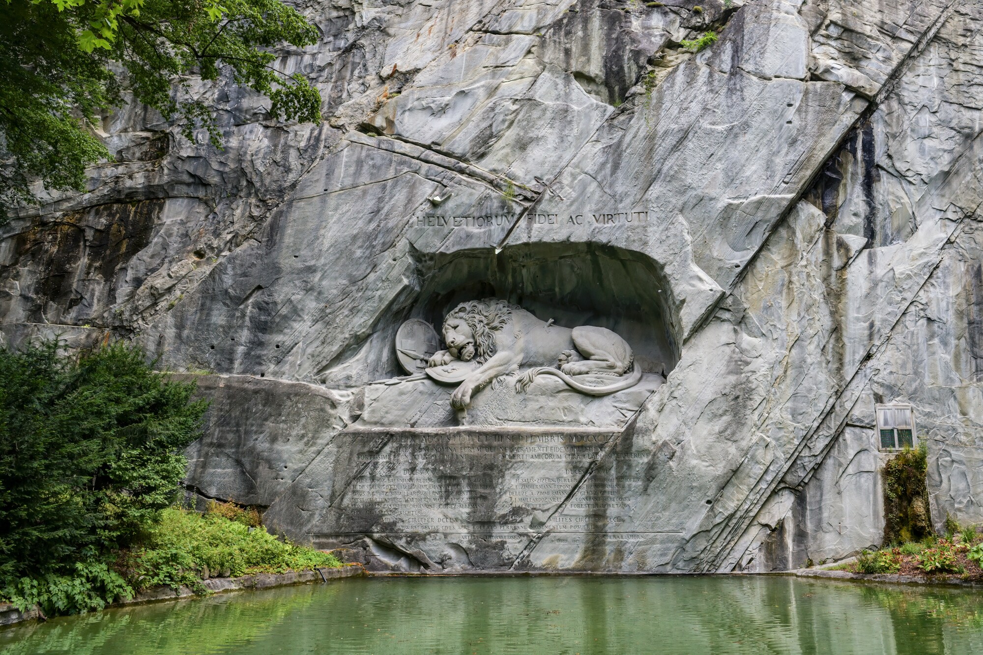 Steinskulptur in Löwenform in einer Felswand über einem Teich. Steinskulptur in Löwenform in einer Felswand über einem Teich.