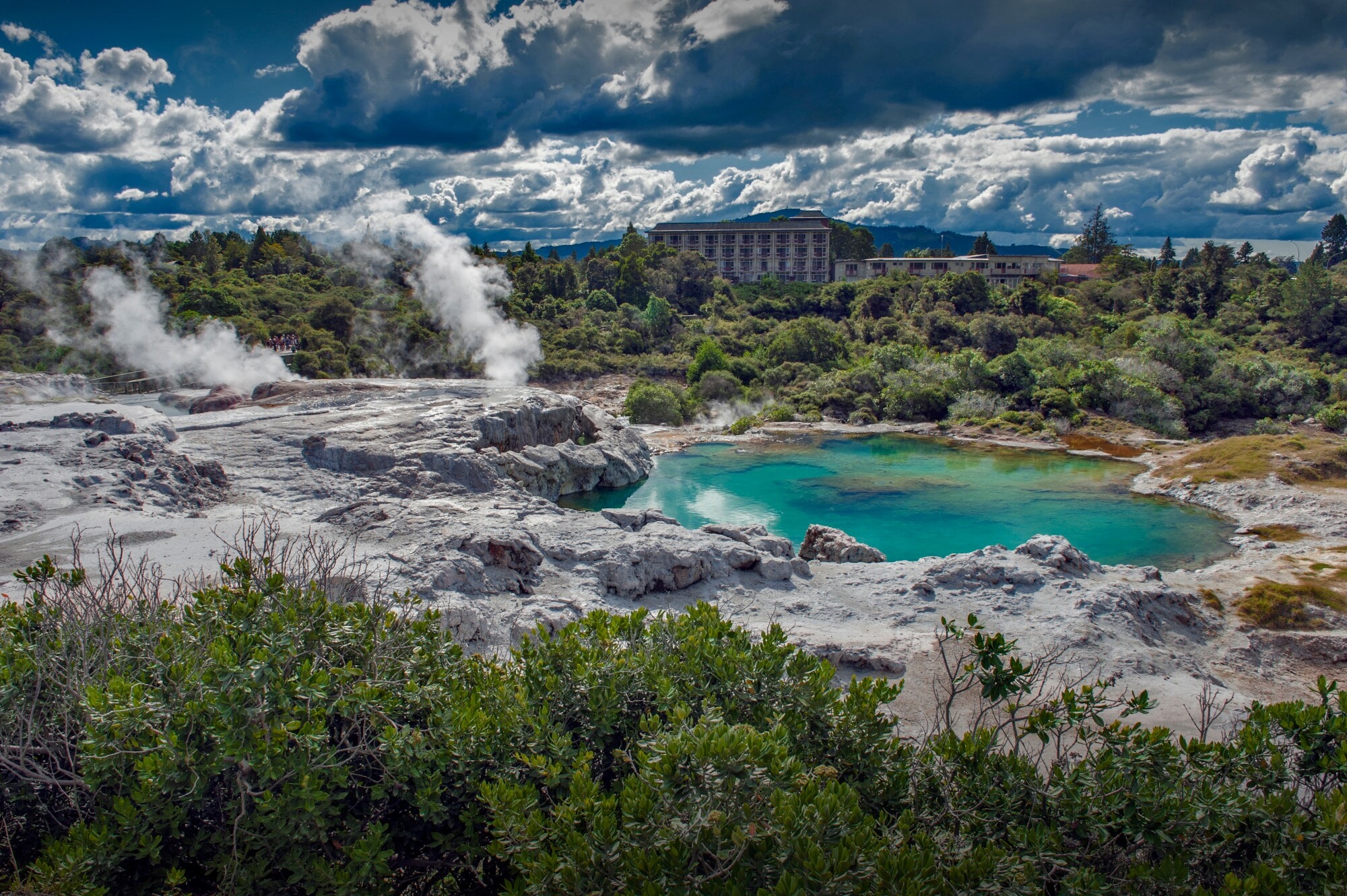 Blick auf Landschaft mit dampfenden Geysiren und grünblauem Wasser Blick auf Landschaft mit dampfenden Geysiren und grünblauem Wasser