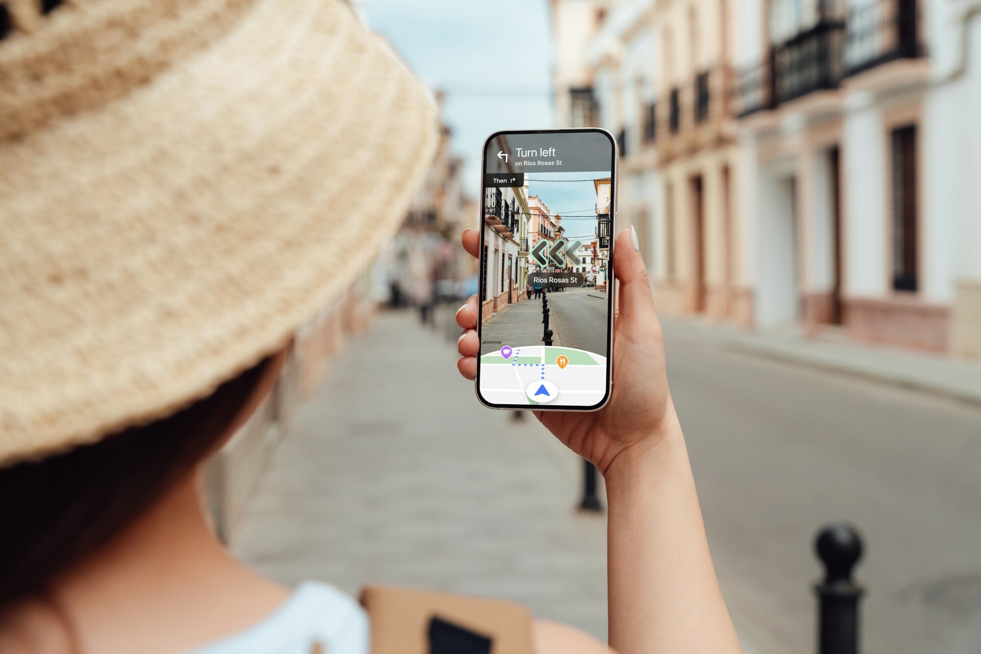 Eine Frau navigiert mit Blick auf ihr Smartphone per Live View von Google Maps durch eine Straße.