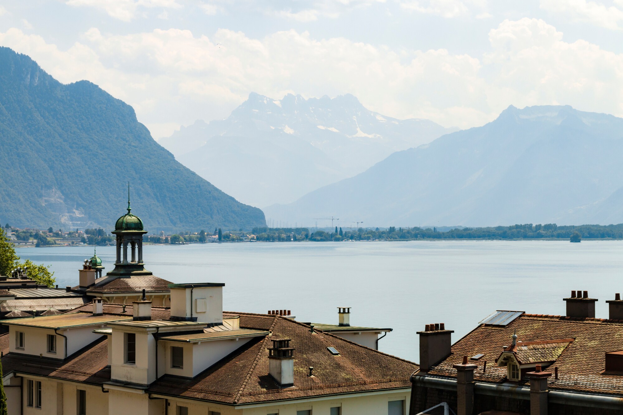 Der Genfer See mit Altbauten im Vordergrund, im Hintergrund die Alpen.