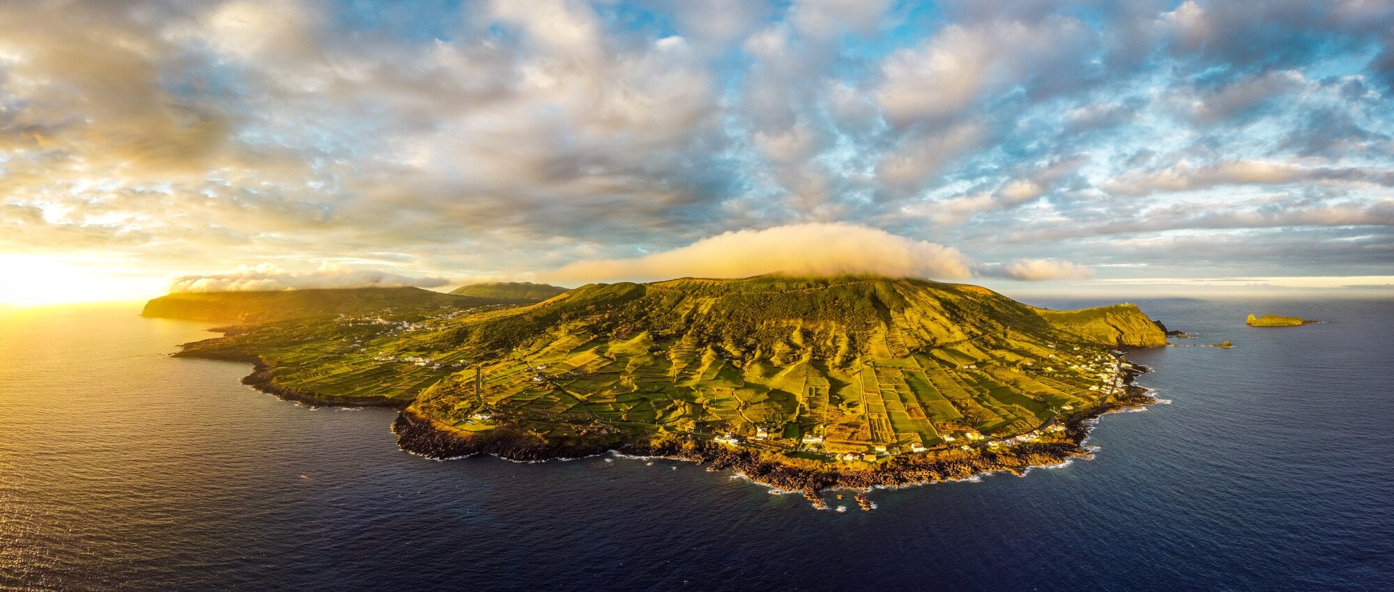 Luftaufnahme der Vulkaninsel Graciosa mit sanften, grünen Hügellandschaften bei Sonnenuntergang. Luftaufnahme der Vulkaninsel Graciosa mit sanften, grünen Hügellandschaften bei Sonnenuntergang.