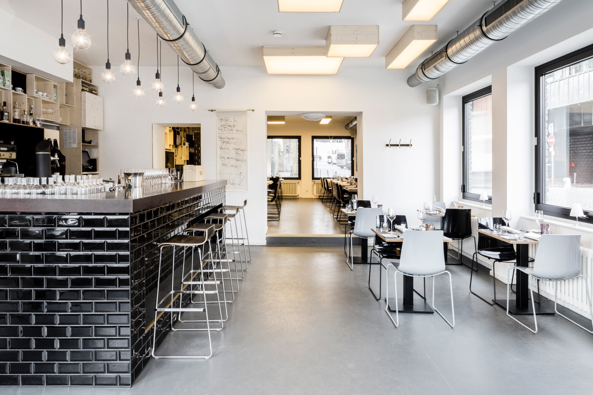 Speiseraum mit Tresen eines modernen Restaurants im industriellen Design und schwarz-weißer Farbgestaltung.