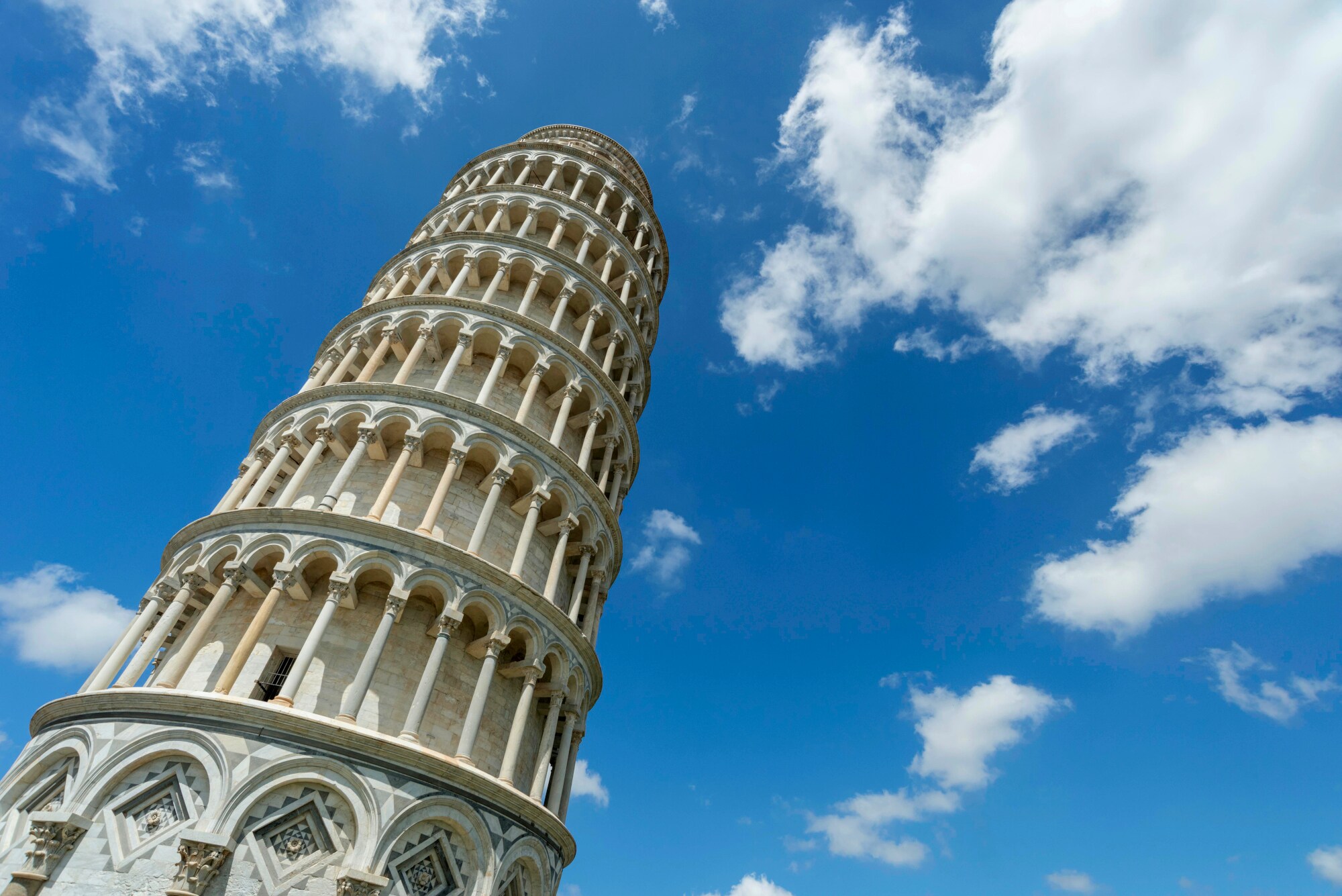 Der Schiefe Turm von Pisa vor blauem Himmel mit Wolken aus der Froschperspektive. Der Schiefe Turm von Pisa vor blauem Himmel mit Wolken aus der Froschperspektive.