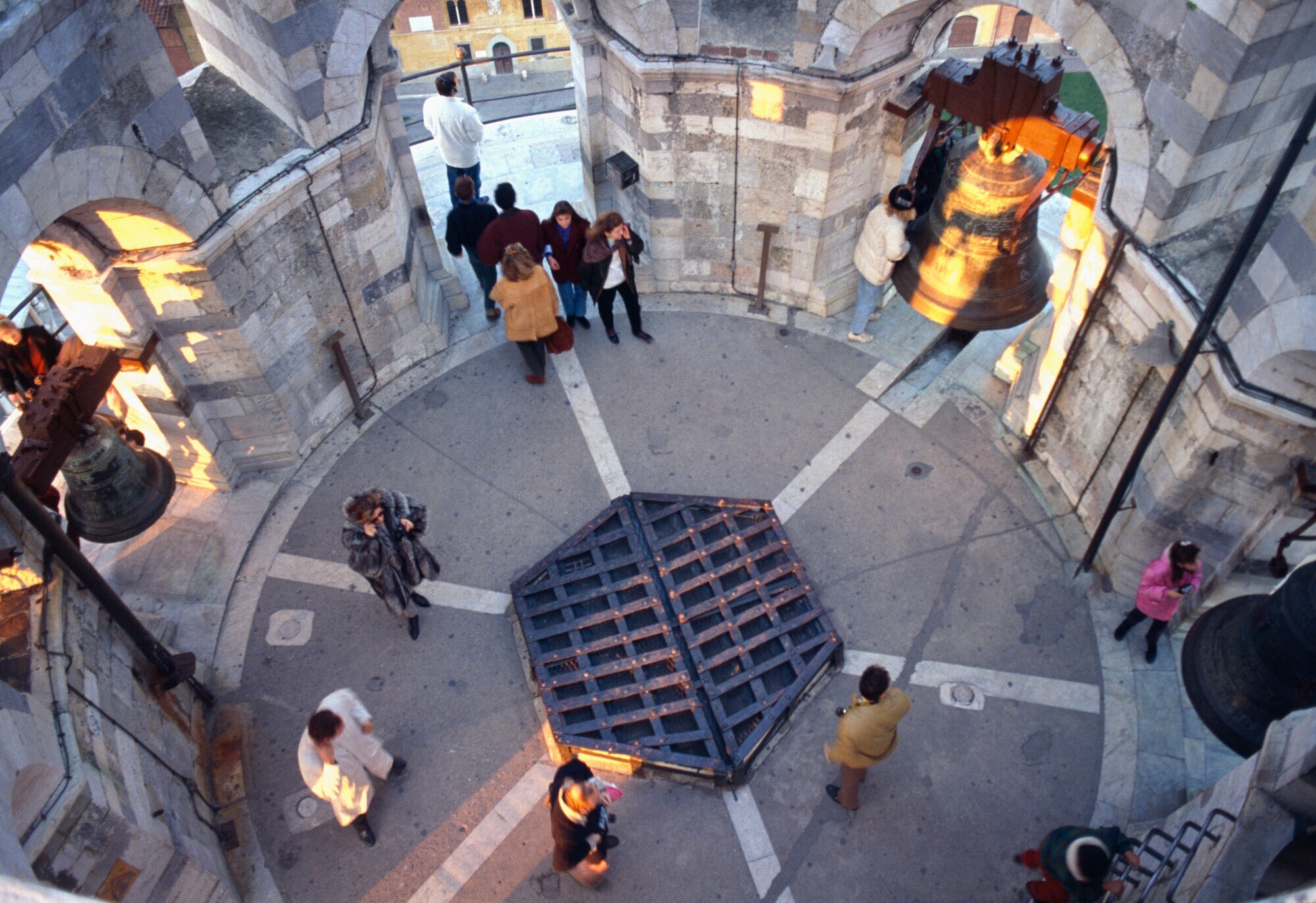 Aufsichtaufnahme von Personen auf einer Aussichtsplattform eines runden Turms mit Glocken. Aufsichtaufnahme von Personen auf einer Aussichtsplattform eines runden Turms mit Glocken.