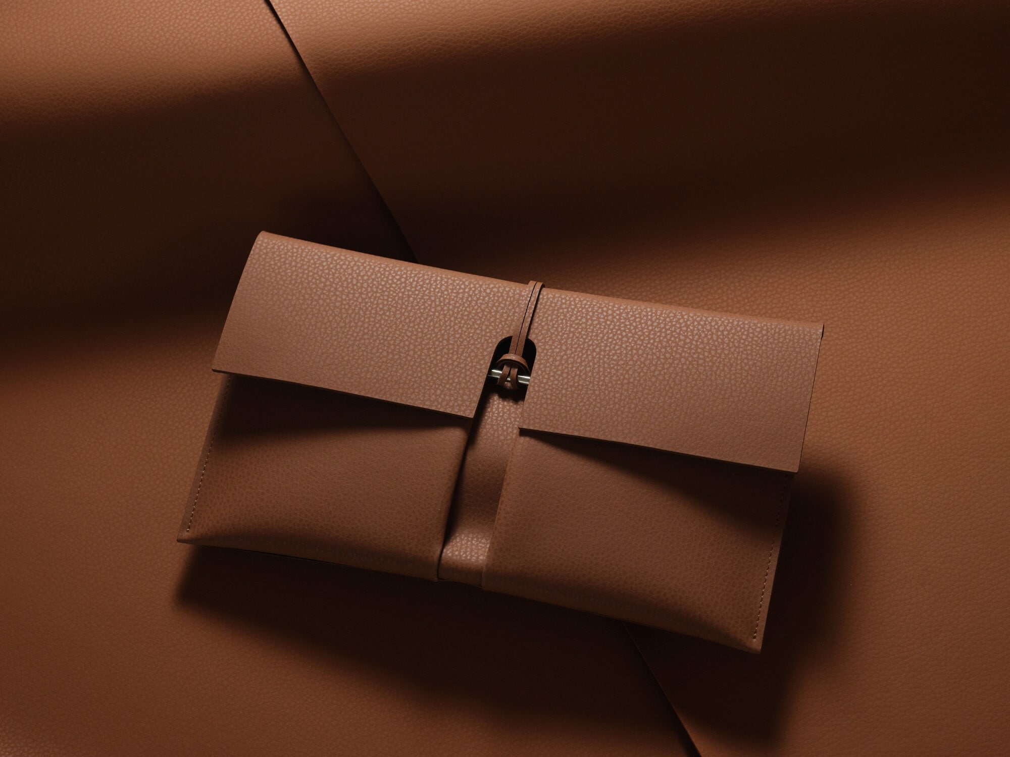 Eine moderne Clutch aus braunem Lederimitat im minimalistischen Design auf einem Untergrund aus braunem Lederimitat.