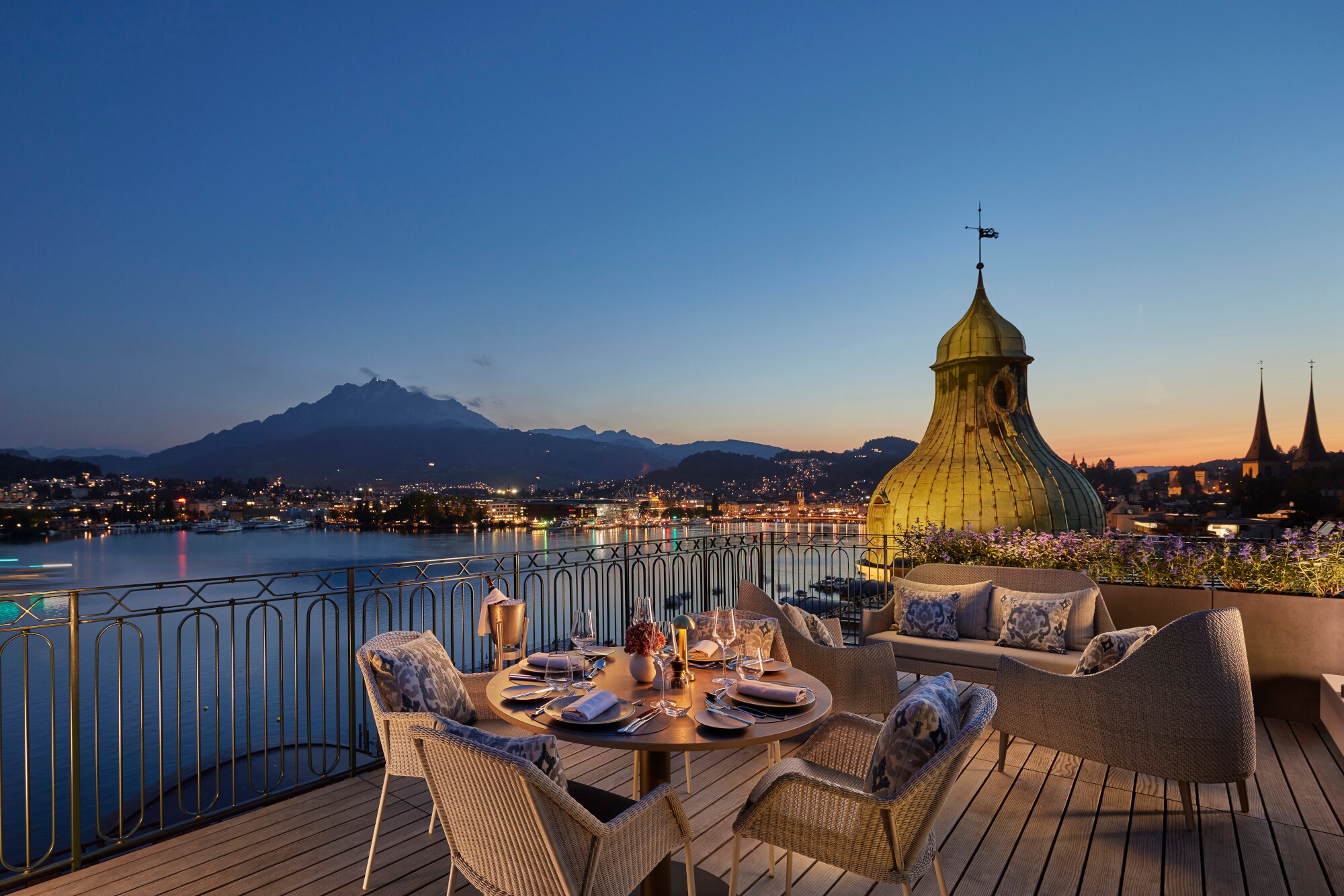 Elegante Hotelterrasse am See mit Blick auf Luzern in der Abenddämmerung.