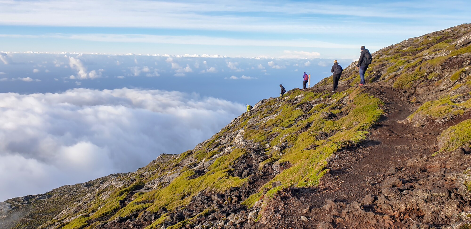 Der Personen an einem Berghang oberhalb der Wolkendecke.