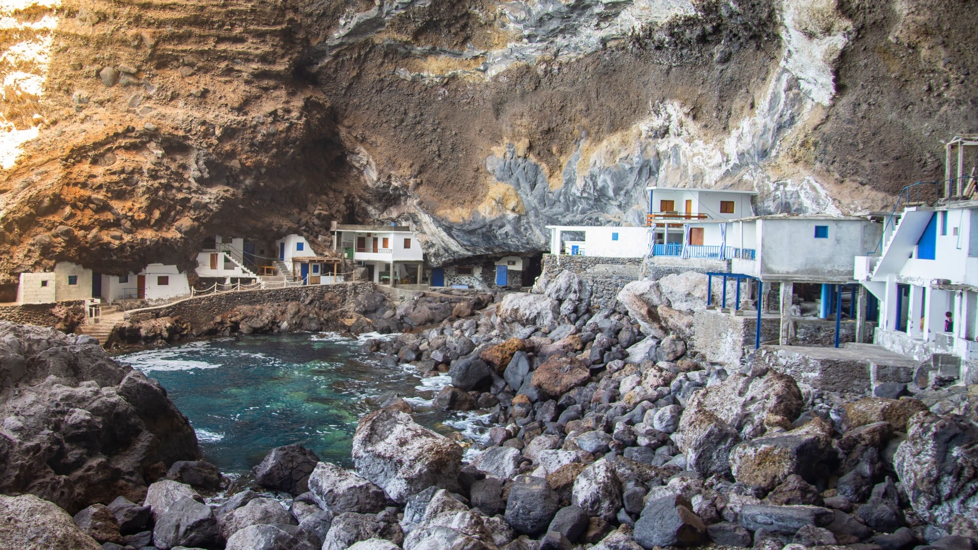 Eine kesselartige Felsbucht mit in den Hang gebauten, weißen Steinhütten. Eine kesselartige Felsbucht mit in den Hang gebauten, weißen Steinhütten.
