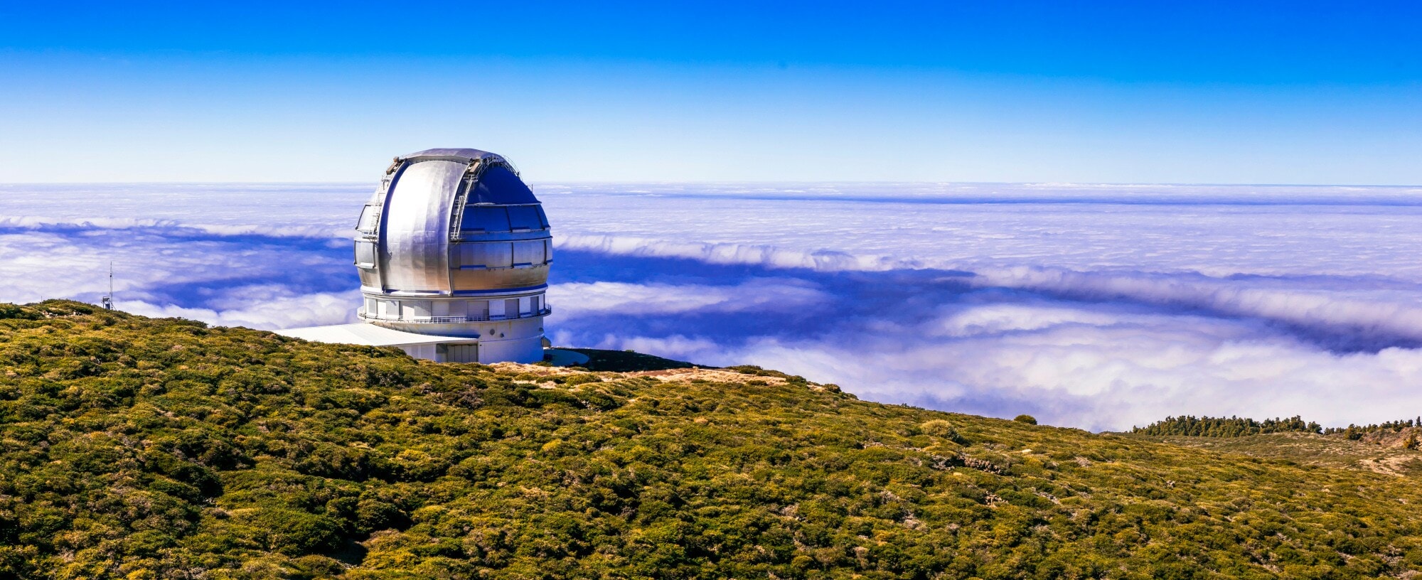 Ein kugelförmiges Observatorium auf einem grünen Bergplateau über der Wolkendecke. Ein kugelförmiges Observatorium auf einem grünen Bergplateau über der Wolkendecke.